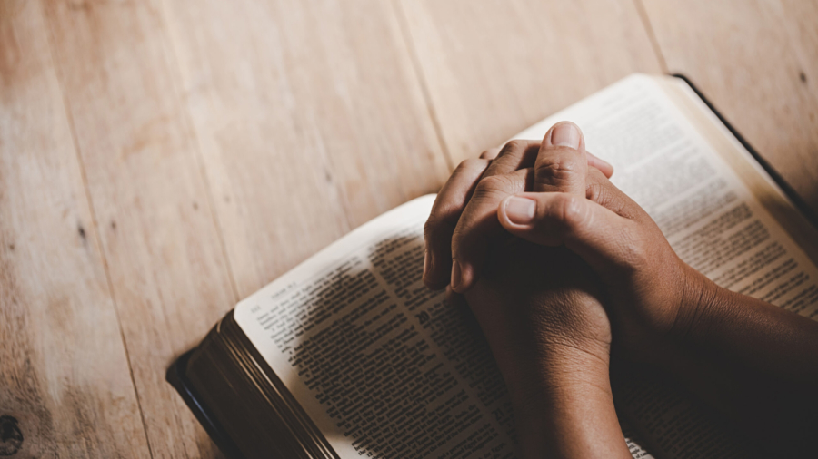 Spirituality and religion, Hands folded in prayer on a Holy Bible in church concept for faith.